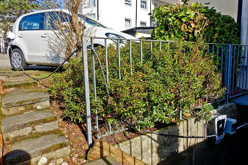 A wall-mounted EV charger at a private house, plugged into a small electric car